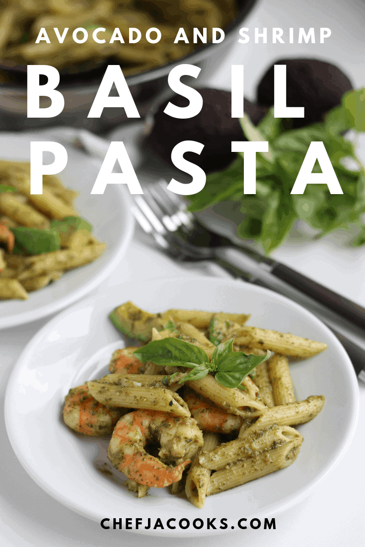 Penne pasta with shrimp, avocado and basil on a plate. Towards the back, frying pan, two avocados and basil leaves are on the table.