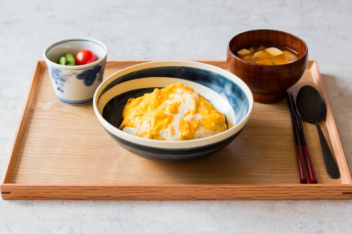 Omurice, miso soup, and salad saved on a tray.